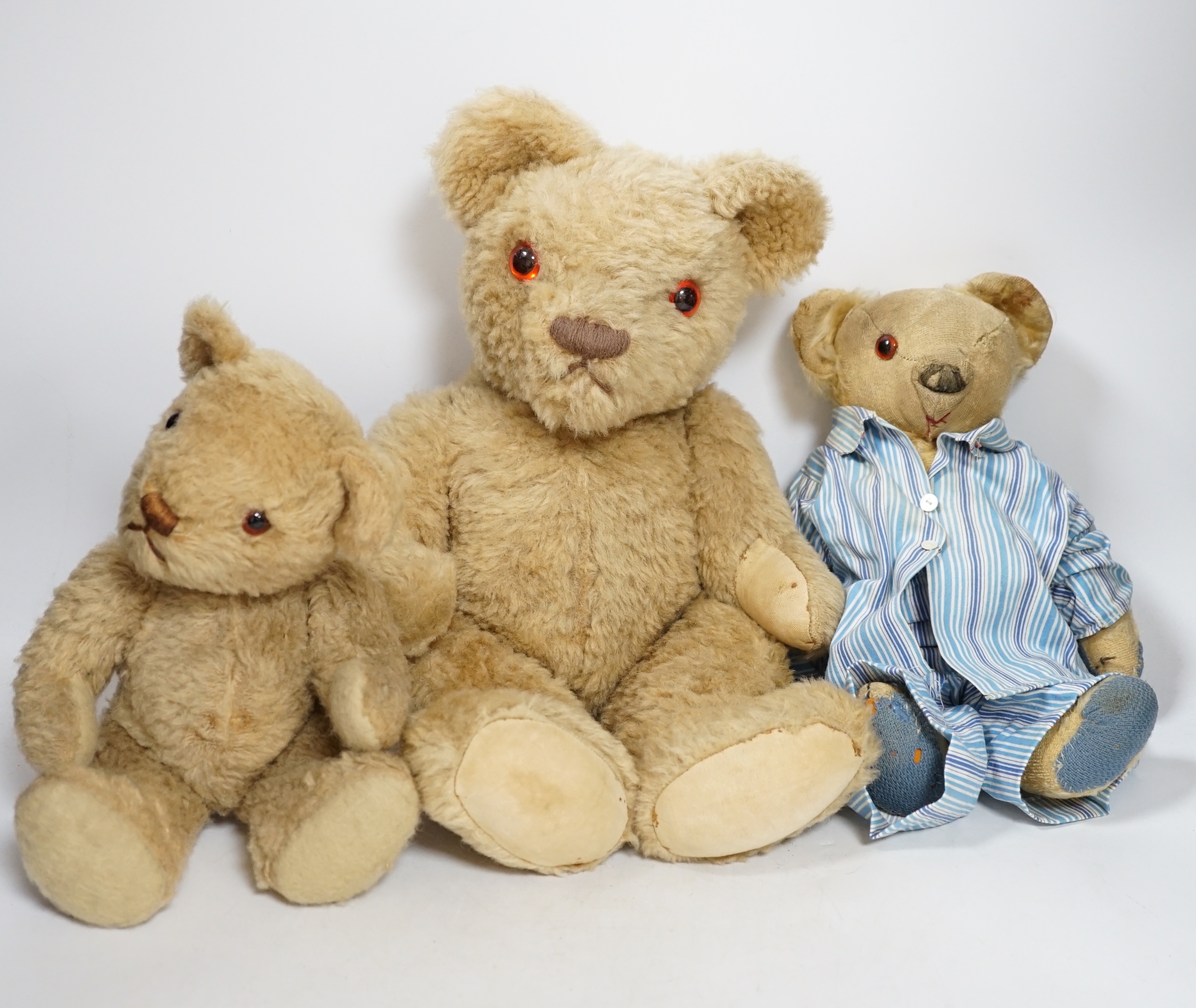 Two Invicta bears, 30cm and 45cm, some wear, and a Merrythought bear, dressed in vintage dressing gown and pyjamas, 32cm high, with hair loss